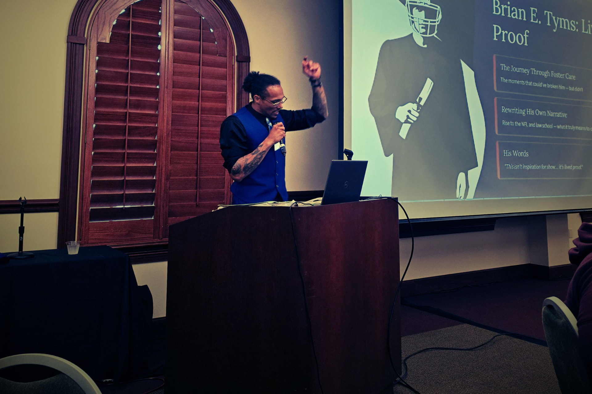 Brian E. Tyms speaking to an audience with his hand raised